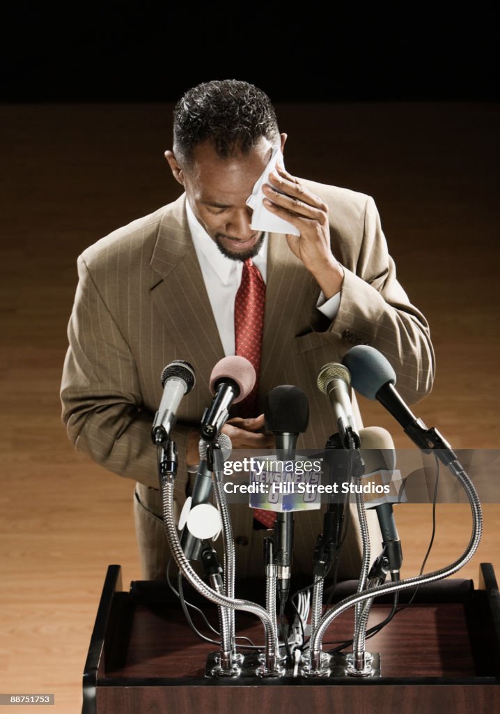 African American man sweating at press conference podium