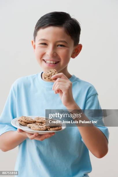 mixed race boy eating cookies - boy holding picture cut out stockfoto's en -beelden