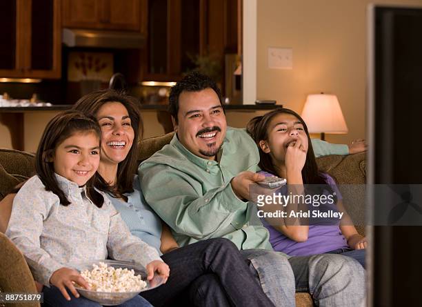 hispanic family watching television together - familia viendo la television fotografías e imágenes de stock