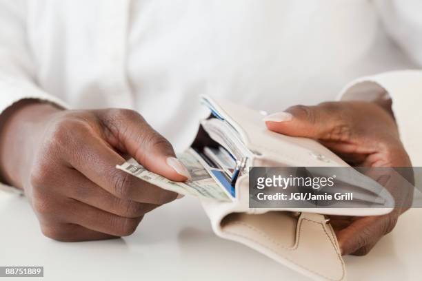 african woman taking money out of wallet - lady wallet stock-fotos und bilder