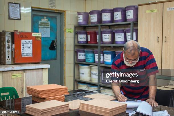 An employee records data after examining sample tiles in the laboratory at the Shabbir Tiles & Ceramics Ltd. Production facility in Karachi,...