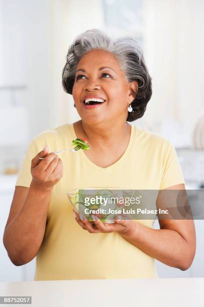 african woman eating healthy salad - mouth thinking stockfoto's en -beelden