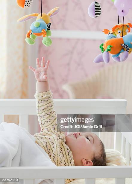 Mixed Race Baby Girl Reaching For Toy Mobile, Foto de stock