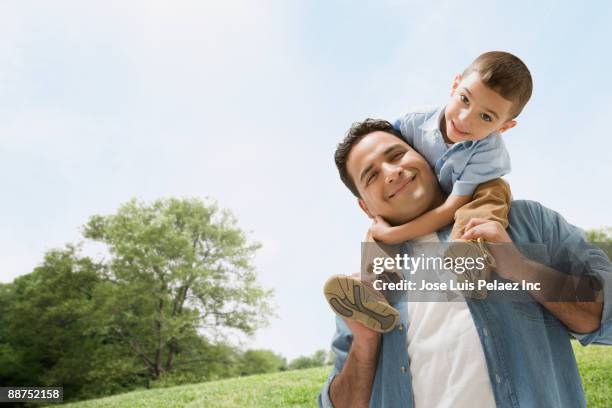 hispanic father carrying son on shoulders - father and son park stock pictures, royalty-free photos & images
