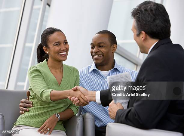african couple shaking hands with financial advisor - happy ending bildbanksfoton och bilder