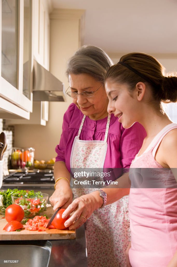 Hispanic grandmother and granddaughter cutting vegetables