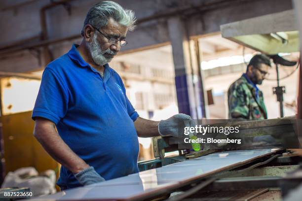 An employee marks a damaged tile moving along a conveyor at the Shabbir Tiles & Ceramics Ltd. Production facility in Karachi, Pakistan, on Wednesday,...