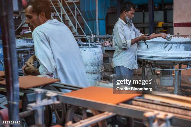 An employee examines the viscosity of a glaze at the Shabbir Tiles & Ceramics Ltd. Production facility in Karachi, Pakistan, on Wednesday, Dec. 6,...
