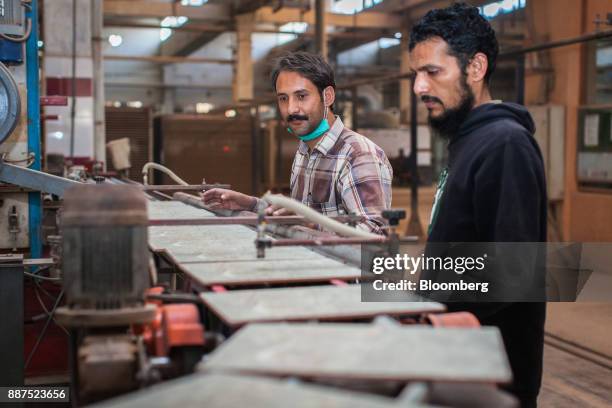 Employees monitor tiles exiting a kiln on a conveyor at the Shabbir Tiles & Ceramics Ltd. Production facility in Karachi, Pakistan, on Wednesday,...