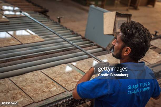 An employee removes a damaged tile from a conveyor at the Shabbir Tiles & Ceramics Ltd. Production facility in Karachi, Pakistan, on Wednesday, Dec....