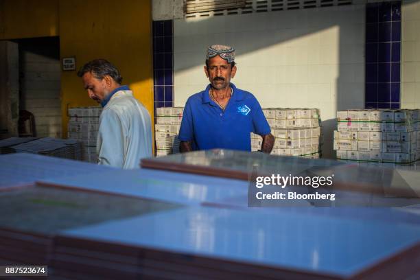 An employee separates damaged tiles before packing into boxes at the Shabbir Tiles & Ceramics Ltd. Production facility in Karachi, Pakistan, on...