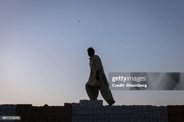 Driver walks across boxes of tiles stacked on a truck at the Shabbir Tiles & Ceramics Ltd. Production facility at dusk in Karachi, Pakistan, on...