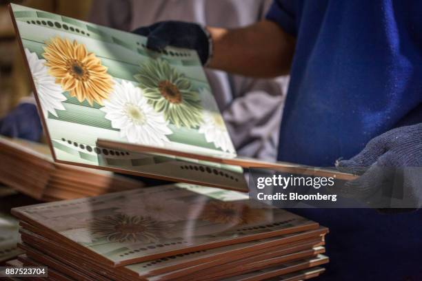 An employee checks tiles before packing into the boxes at the Shabbir Tiles & Ceramics Ltd. Production facility in Karachi, Pakistan, on Wednesday,...