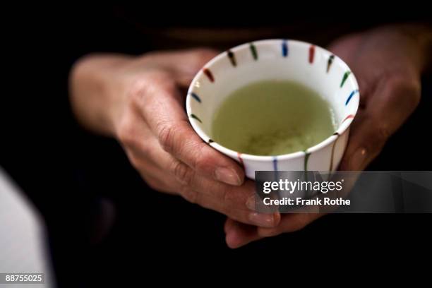 a cup with green tea hold with hands - japanese tea stock pictures, royalty-free photos & images