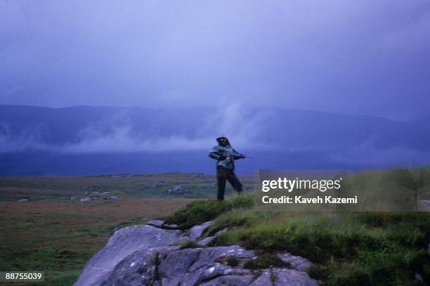 Trainee member of the Provisional Irish Republican Army keeps watch while his comrades practice guerilla warfare tactics in a secret location in the...