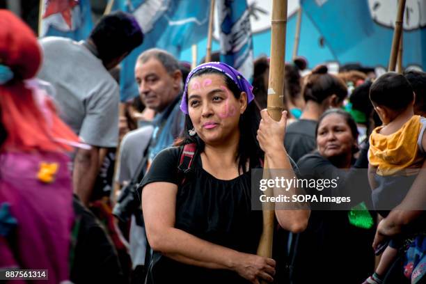 Leaning against a bamboo support pole, a protestor carries a banner down Avenida de Mayo. Marching from the nation's iconic Congreso buildings to...