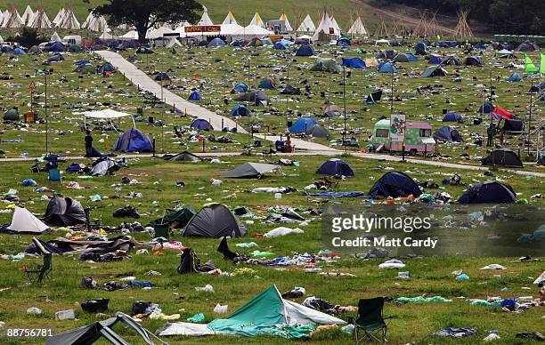 People pass discarded tents and rubbish on the start of the big clear-up of the Glastonbury Festival site at Worthy Farm, Pilton on June 29, 2009...