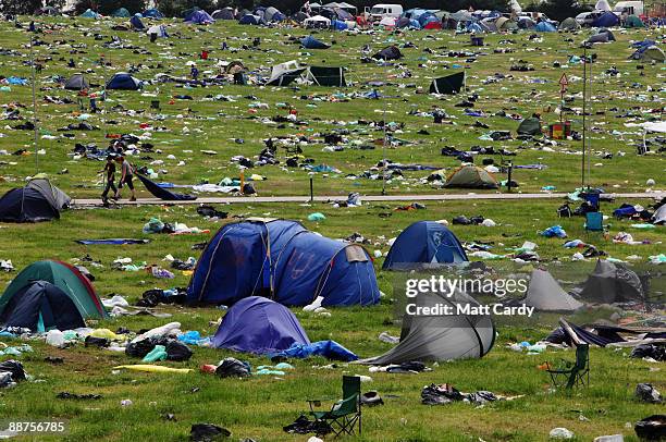 People pass discarded tents and rubbish on the start of the big clear-up of the Glastonbury Festival site at Worthy Farm, Pilton on June 29, 2009...