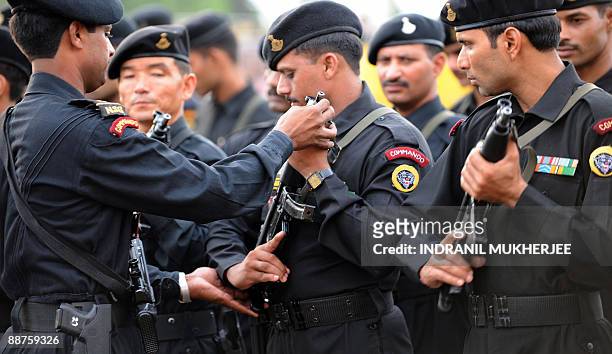 Senior adjusts the gun position of a National Security Guard commando standing in formation during the inuaguration of the NSG Mumbai Hub by Home...