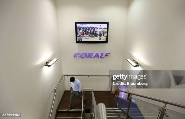 Customer moves past a television screen showing a horse race event as he enters a betting shop, operated by Ladbrokes Coral Group Plc., in London,...