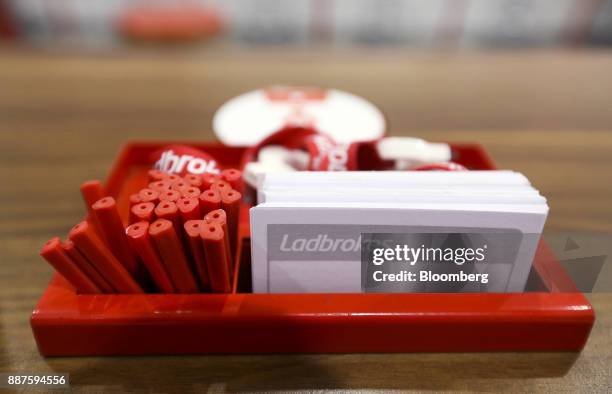 Box of betting slips and pens sit on a counter inside a betting shop, operated by Ladbrokes Coral Group Plc., in London, U.K., on Friday, July 24,...