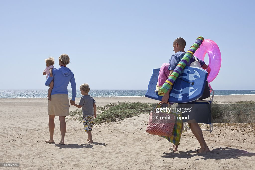 Mother with children on beach, father behind