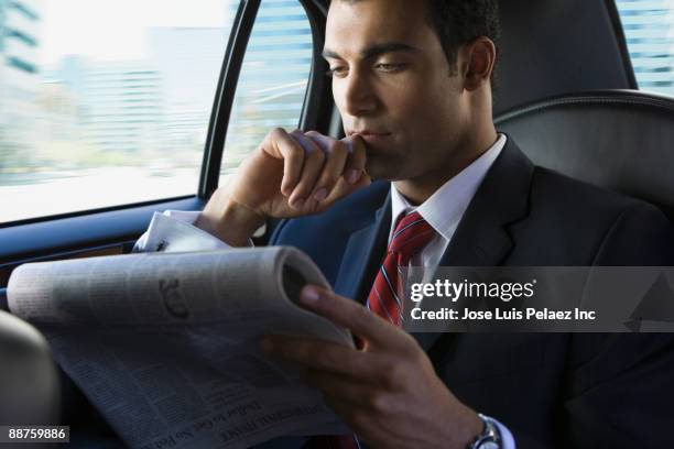 hispanic businessman reading newspaper in limousine - junger mann liest zeitung stock-fotos und bilder