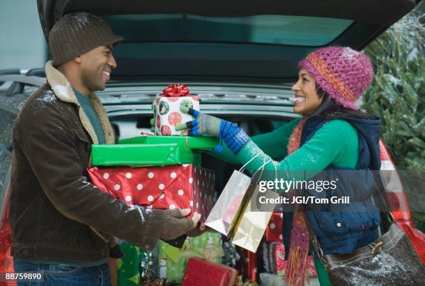 couple unloading christmas presents from car trunk - xmas car stock pictures, royalty-free photos & images