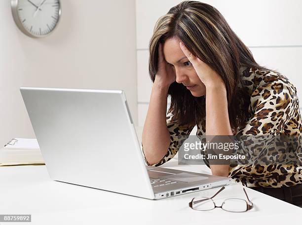 hispanic businesswoman looking at laptop with head in hands - overdoing stock pictures, royalty-free photos & images