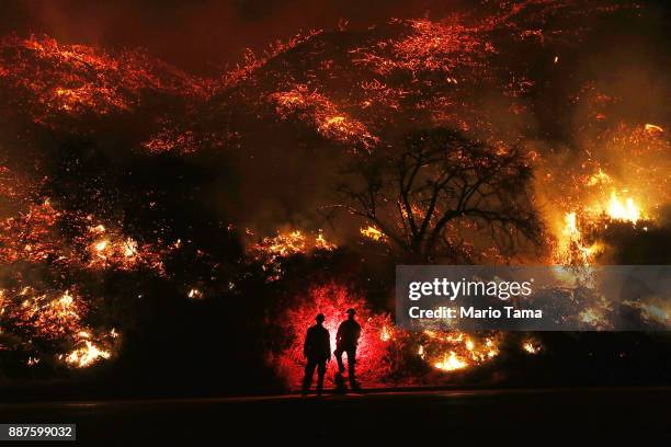 Firefighters monitor a section of the Thomas Fire along the 101 freeway on December 7, 2017 north of Ventura, California. The firefighters...