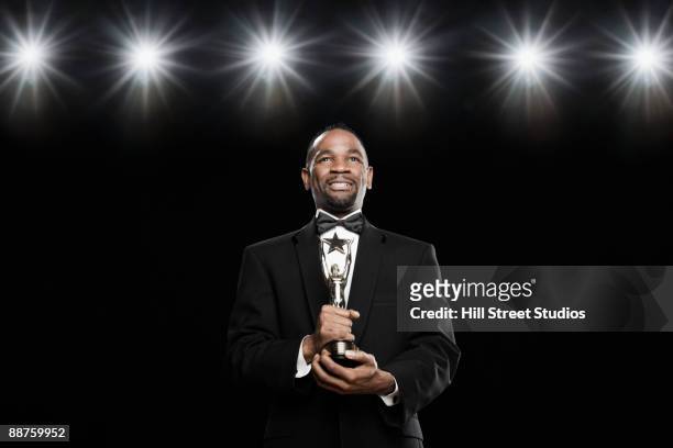 african american man in tuxedo holding trophy - winners podium stockfoto's en -beelden