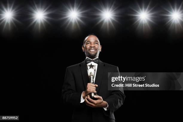 african american man in tuxedo holding trophy - awards show stock pictures, royalty-free photos & images