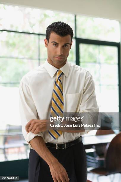 hispanic businessman rolling up sleeves - sleeve roll stock pictures, royalty-free photos & images