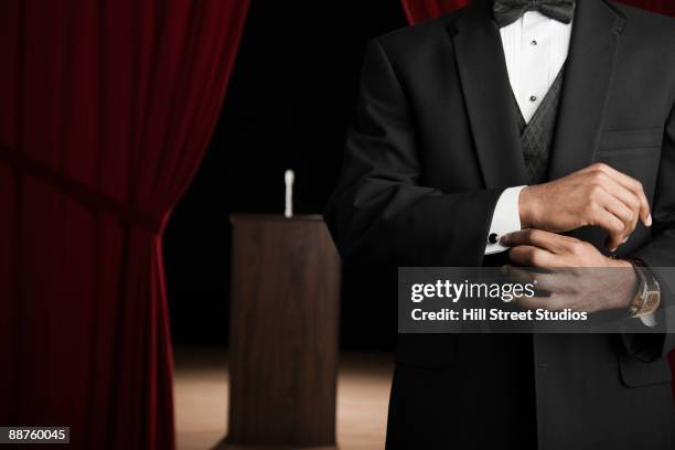 african american man in tuxedo adjusting cufflinks backstage - cufflinks stockfoto's en -beelden