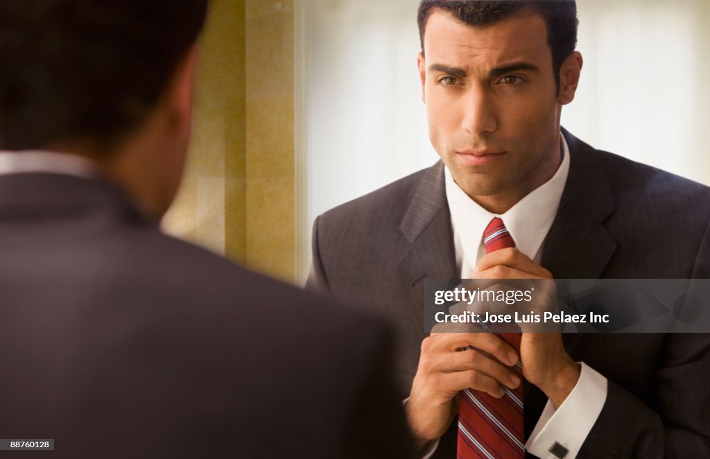 Hispanic businessman adjusting tie