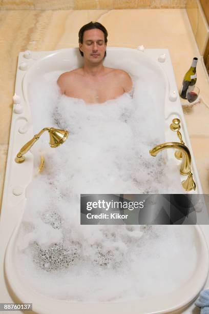 hispanic man relaxing in bubble bath - bubble bath bottle stock pictures, royalty-free photos & images