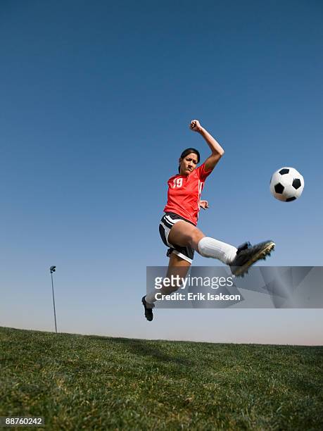 mixed race woman kicking soccer ball - blue sports ball stock pictures, royalty-free photos & images