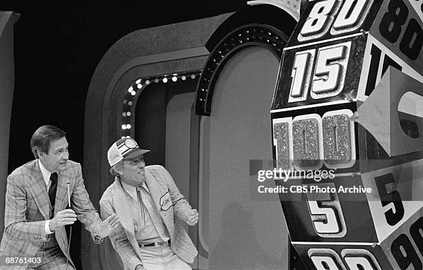 Bob Barker and a contestant named James look on as the Big Wheel spins around on the game show 'The Price Is Right', February 1978.