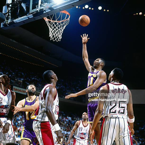 Elden Campbell of the Los Angeles Lakers shoots a layup against Robert Horry and Hakeem Olajuwon of the Houston Rockets in Game Three of the Western...