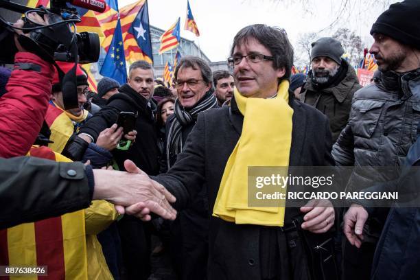Catalonia's deposed regional president Carles Puigdemont and Former Catalan regional president Artur Mas shakes hands with supporters during a...