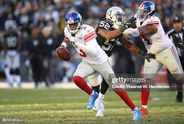 Geno Smith of the New York Giants scrambles away from the pressure of Khalil Mack of the Oakland Raiders during their NFL football game at...