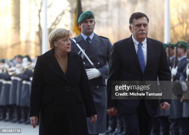 Germany Chancellor Angela Merkel and Chairman of the Presidential Council of Libya and Prime Minister Fayez Mustafa al-Sarraj pass by the honor guard...