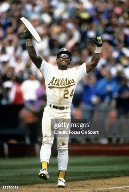 Outfielder Rickey Henderson of the Oakland Athletics holds up the third base bag after stealing it against the New York Yankees given him 939 career...