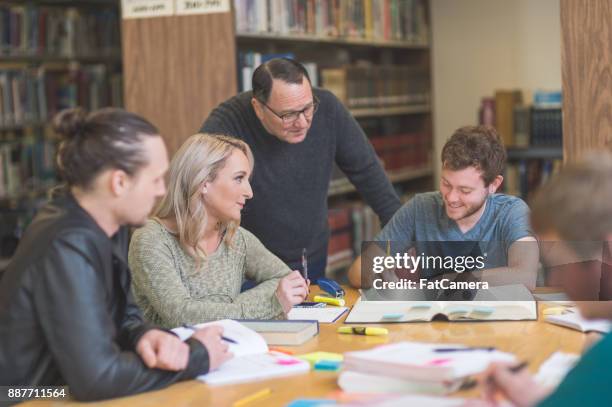 college students study together around a table in the library - university debate stock pictures, royalty-free photos & images