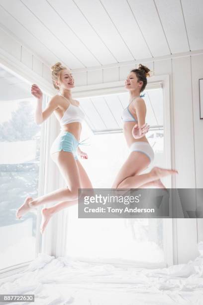 two teen girls jumping on bed - girls in bras photos 個照片及圖片檔