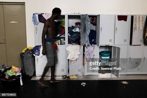 Junior Harris, a displaced resident from the island of Barbuda, gets dressed inside a shelter at a cricket stadium on December 7, 2017 in St John's,...