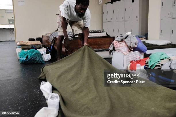 Danny Jeffrey, A displaced resident from the island of Barbuda, makes his bed inside a shelter at a cricket stadium on December 7, 2017 in St John's,...