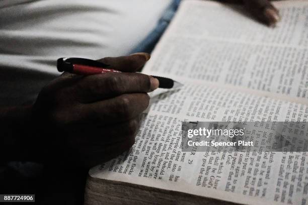 Collen Harris, a practicing Muslim and a displaced resident from the island of Barbuda, reads the Bible to pass time inside a shelter at a cricket...