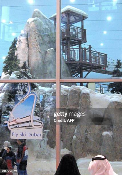 An Emarati couple sit outside Ski Dubai, where their children are enjoying a minus 3 degree Celcius climate, in the Emirates Mall on July 01 2009. As...