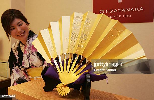 Model displays the golden Japanese fan at jewelry maker Ginza Tanaka Osaka branch on July 1, 2009 in Osaka, Japan. The fan was made to celebrate the...